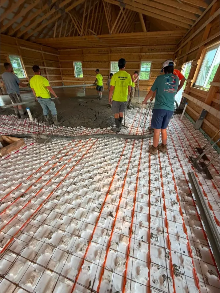 Crew pouring a barndominium floor over radiant heat tubing