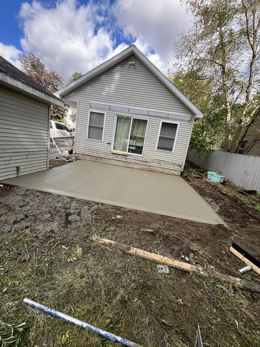 New broom finish concrete slab behind a house with fresh grading around it