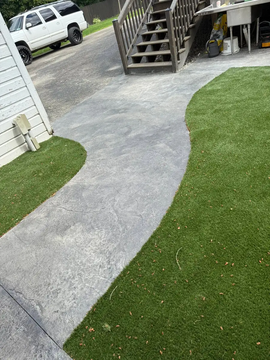 Curved broom finish concrete walkway next to new turf
