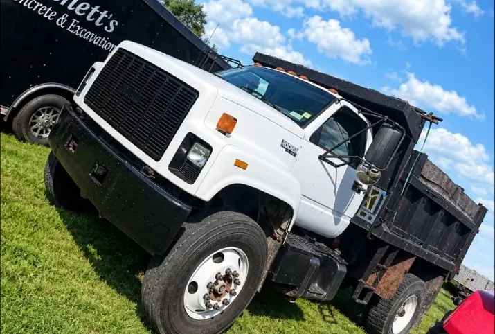 Bennett's white dump truck parked beside the company trailer