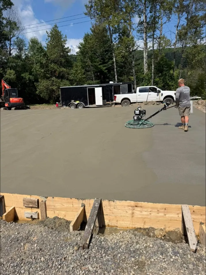Finish & Seal: Power troweling a fresh slab, with the Bennett's trailer, pickup and mini excavator behind