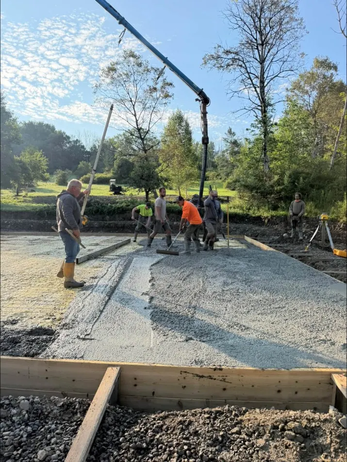 Concrete pump boom placing concrete on a big slab while the crew spreads it