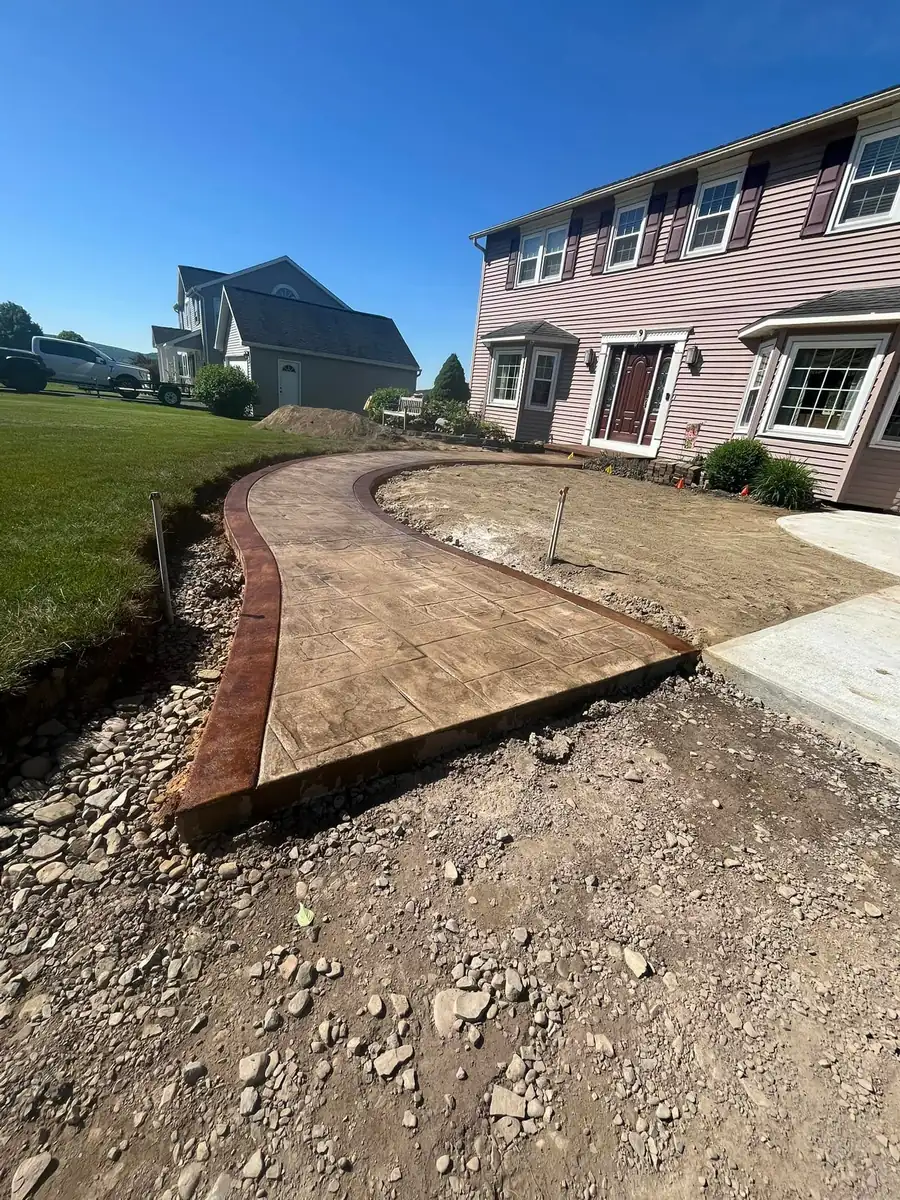 Curved stamped walkway with a red border running to a front porch