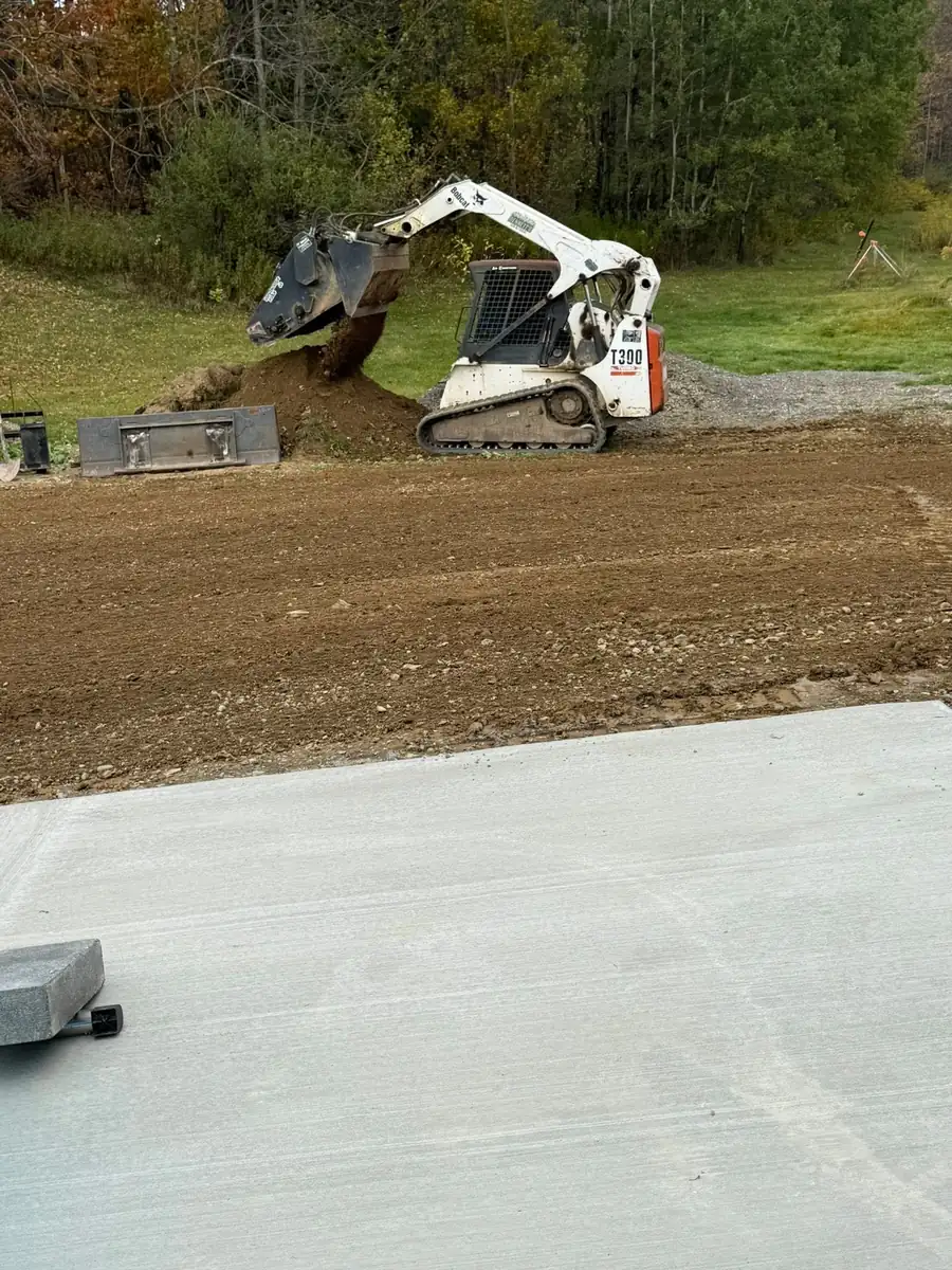 Skid steer prepping the ground beside a new slab