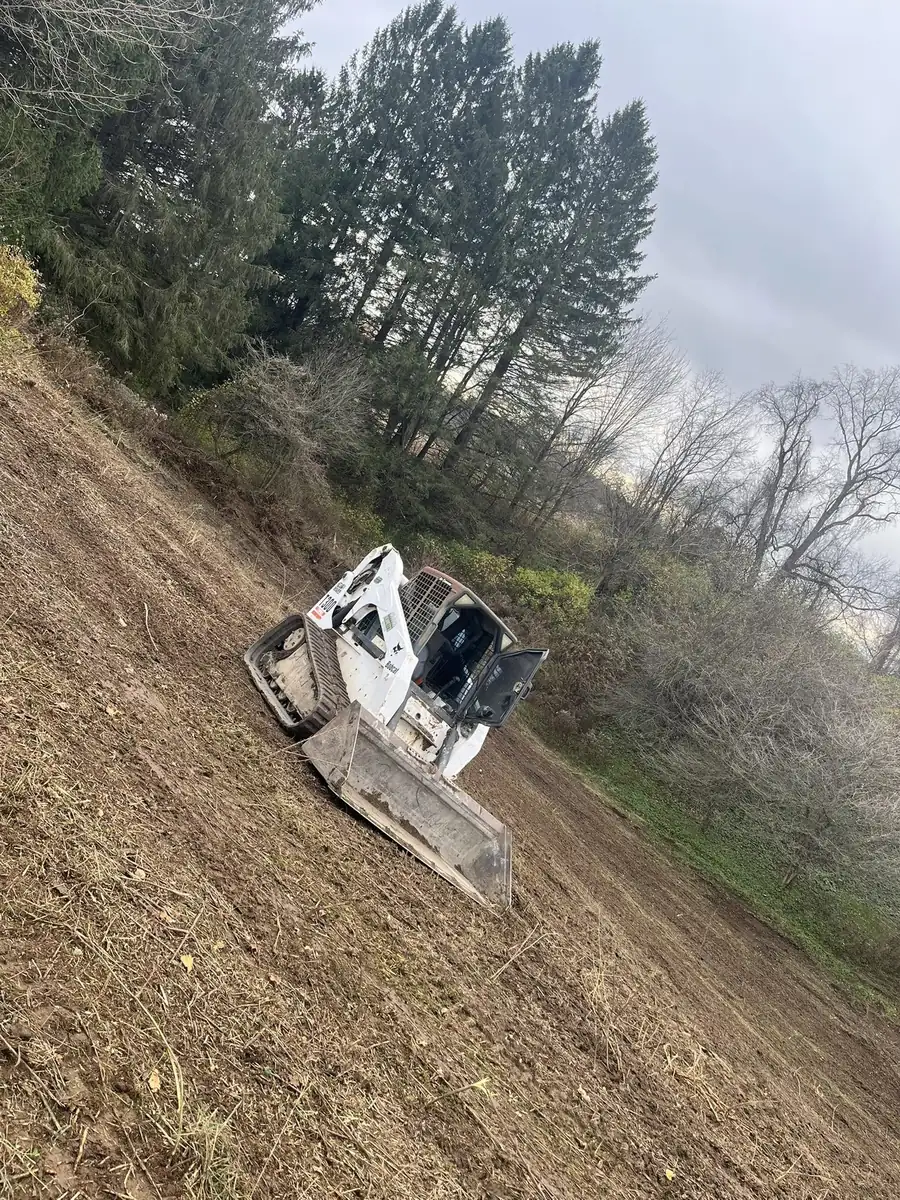 Skid steer working a steep slope while grading