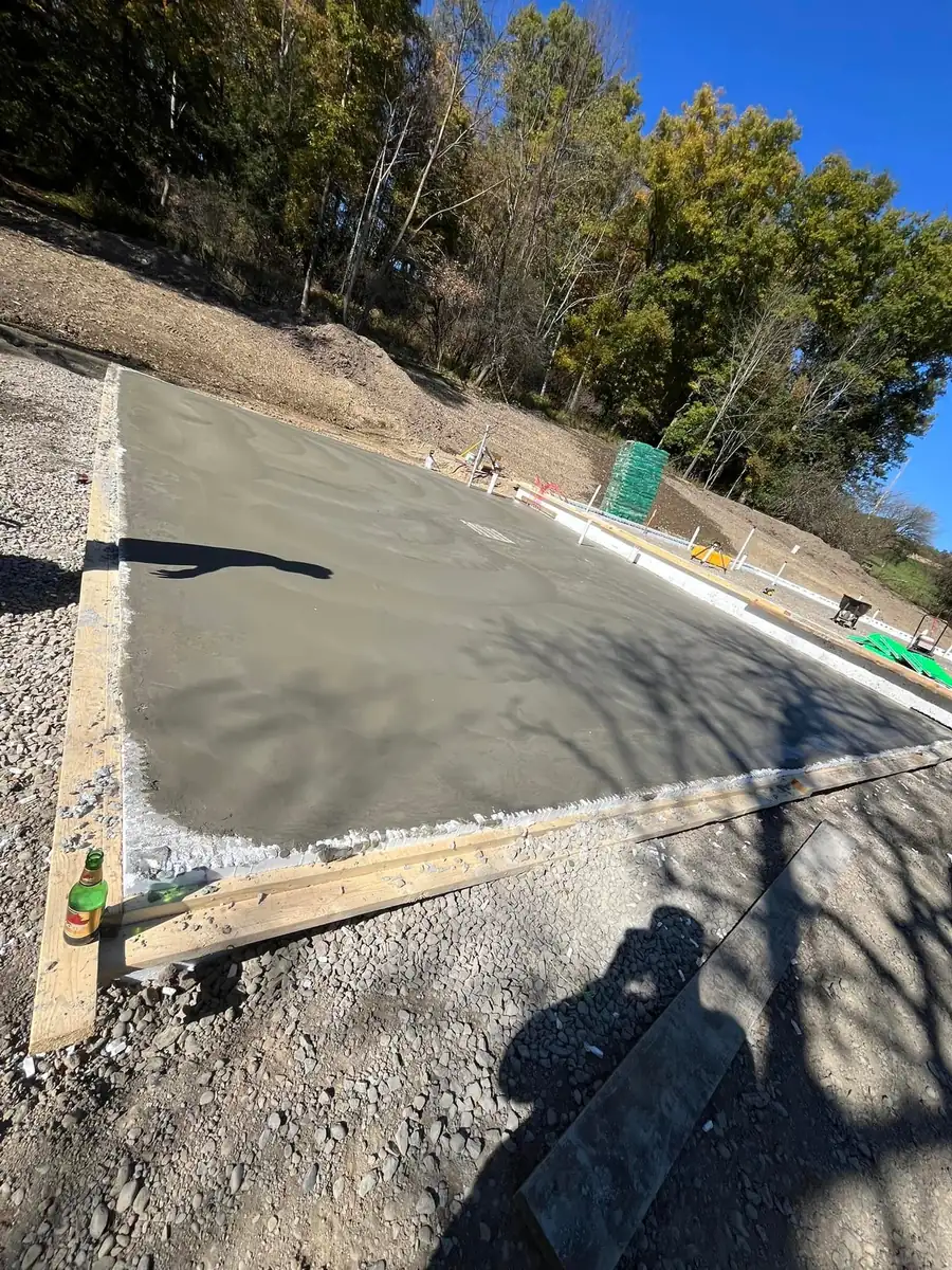 Freshly poured concrete slab inside wood forms on a gravel base
