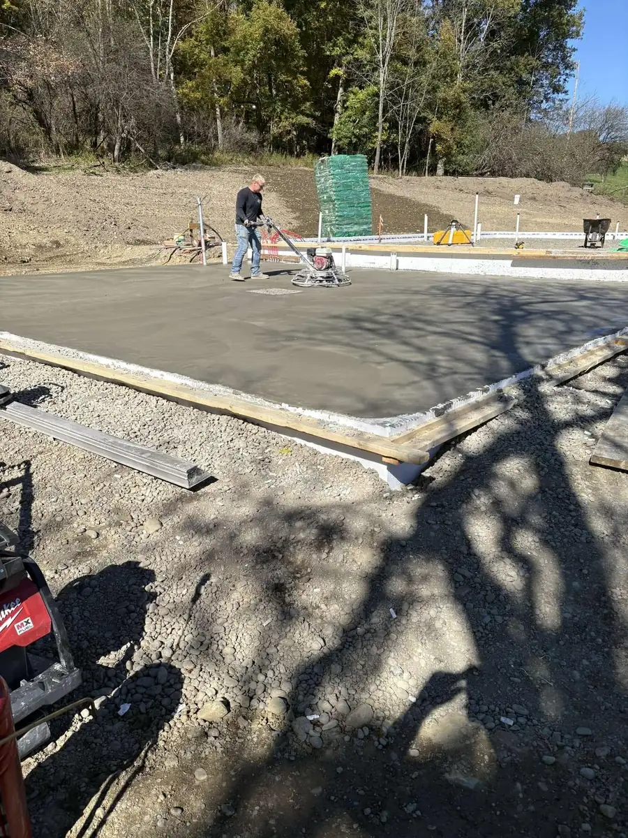 Crew screeding a fresh concrete slab inside wood forms
