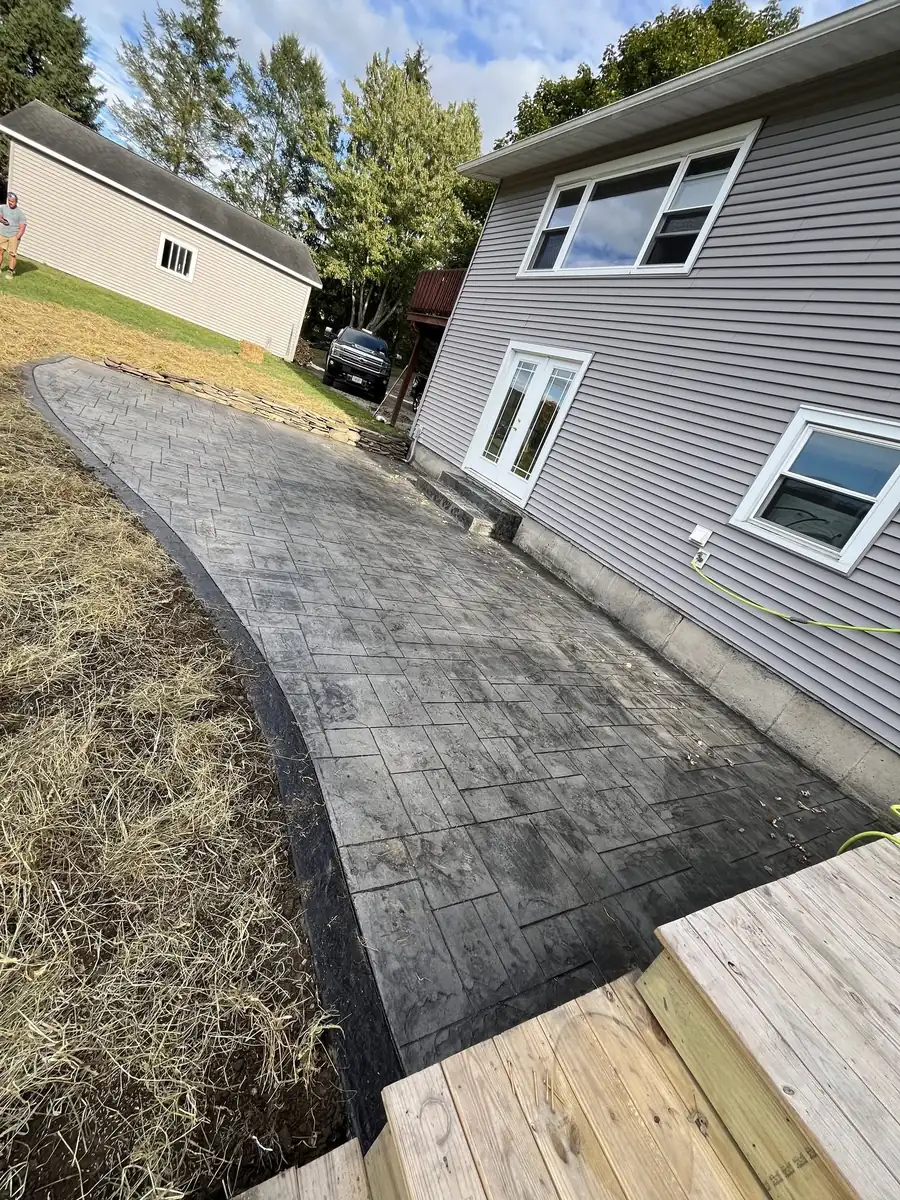 Slate stamped concrete patio along the side of a gray house