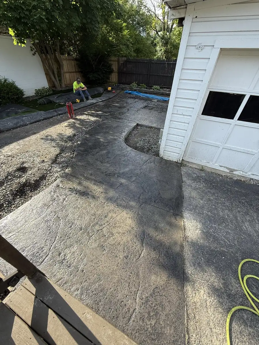 Gray stamped concrete apron leading to a white garage