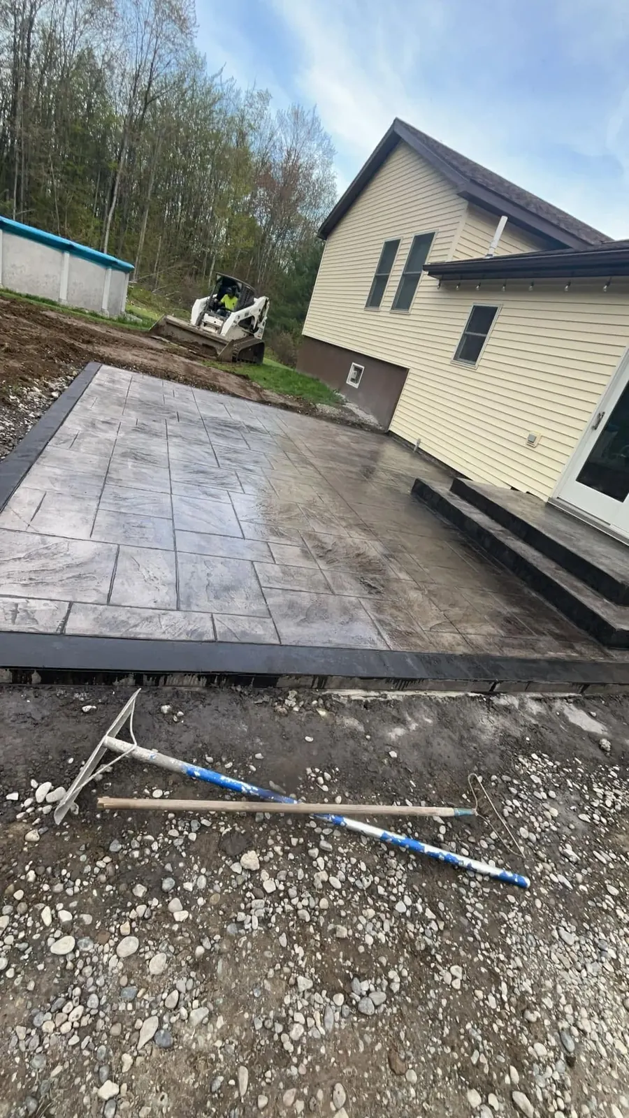 Stamped concrete patio beside a yellow house