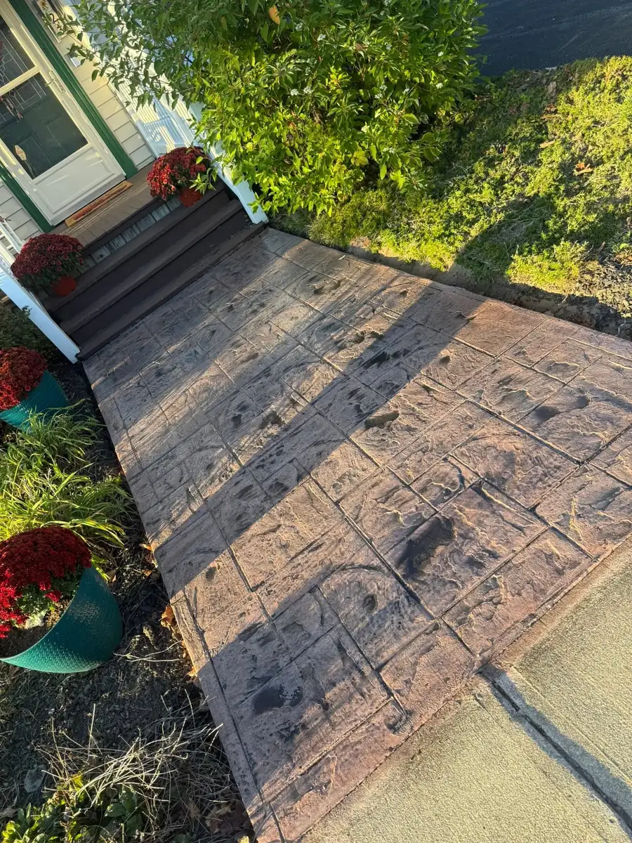 Stamped concrete walkway with planters along the front of a house