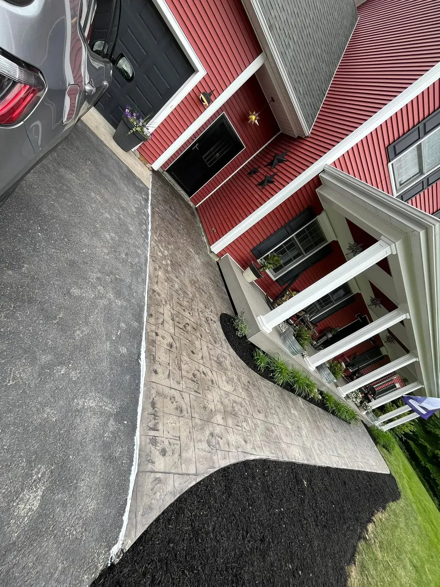 Stamped concrete walkway along a red house
