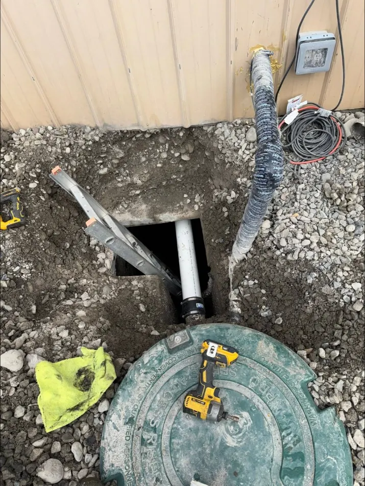 Excavated pipe connection beside a commercial building