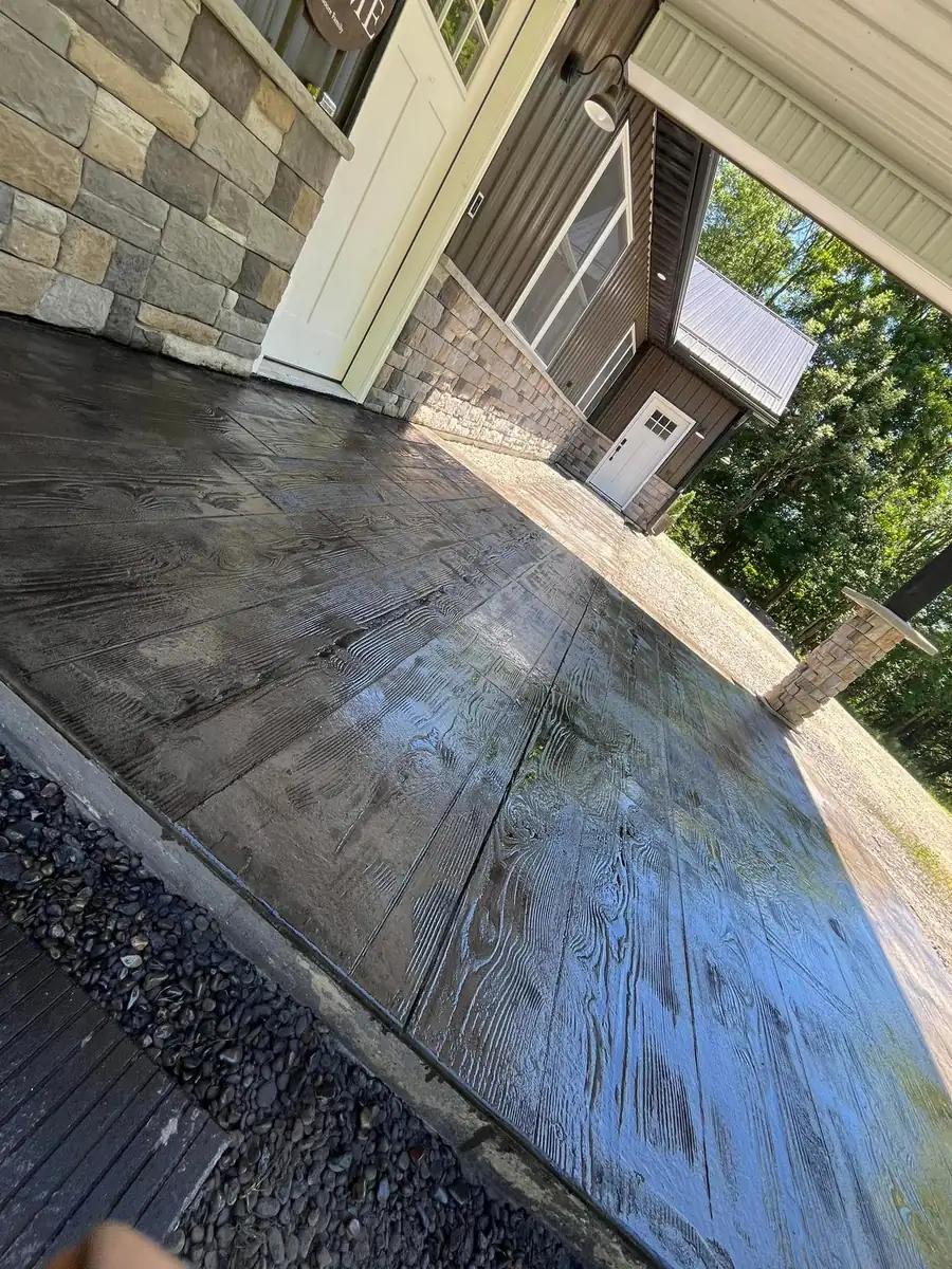 Wood plank stamped concrete porch with a stone veneer wall
