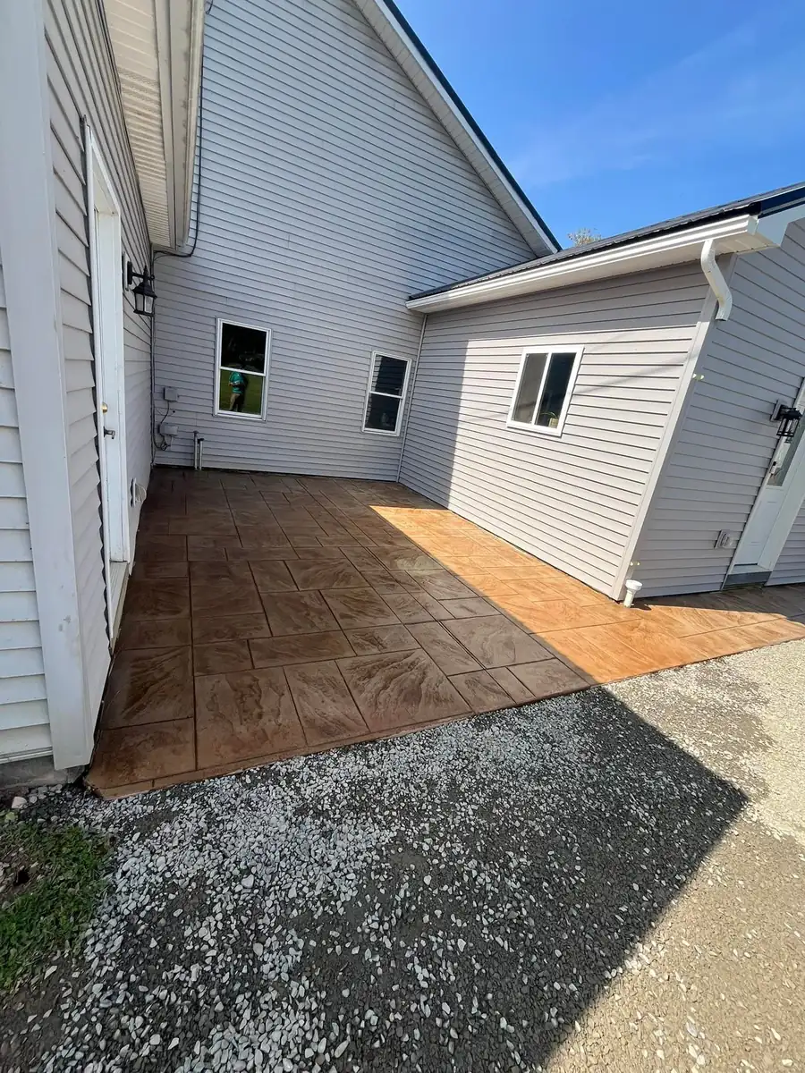 Wood plank stamped concrete patio between two wings of a house